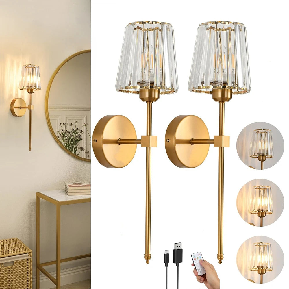 Gold wall sconces with clear glass shades, remote control, and cables on a white background.